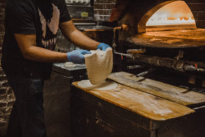 Chef rolling Manousheh dough for pizza